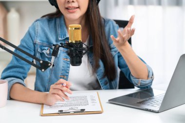 Sosyal medyada kulaklıkla canlı yayın yapan Asyalı sunucu modern stüdyoda yaşam koçluğu veya pazarlama dinleyicilerini selamlıyor. Taktik.