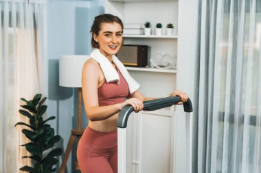 Spor ve atletik bir kadın, evdeki fiziğe ve sağlıklı spor yaşam tarzına uygun vücut egzersizi sırasında koşu bandında koşuyor. Gaiety evde egzersiz eğitimi.