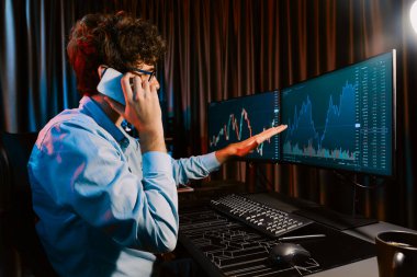 Neon Light Modern Ofis 'te borsa borsası grafiği ile akıllı telefondaki borsacıyla gerçek zamanlı çalışan genç bir tüccar. Dinamik döviz kurunu analiz etme kavramı. Toplayıcı.