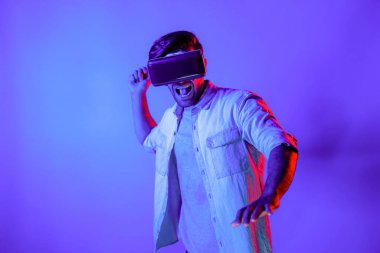 Kafkasyalı bir adam VR cam takıyor ve hareket eden el kol kılıcını tutuyor. Oyuncu, gelecekteki sanal gerçeklik kulaklığını ya da gelecekteki yenilikleri kullanarak meta dünyaya giriyor ya da aksiyon oyunu oynuyor. Sapma.