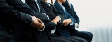 Panoramik afiş ekibi sırada oturup el ele vererek başarılı iş ortaklığını ve iş bulma için profesyonel sinerjiyi, İK işe alım konseptini sembolize ediyor. Kurnaz.