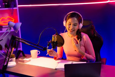 Geceleri podcast 'te olumlu konuşmalar yapan, pembe neon ışıklı modern stüdyoda sunum için dizüstü bilgisayar kullanan, gülümseyen, genç, güzel Asyalı bir etkileyiciydi. Taktik.