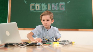 Kameraya karatahta ile bakarken elektronik tahtada çalışan zeki bir öğrenci. Çocuk, kodlama mühendisliği ve yapay zeka kullanarak programlama sistemine hazırlanırken ana tahtayı tamir ediyor. Pedagoji.