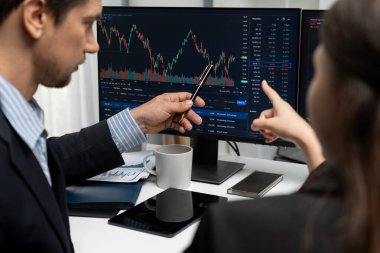 Dinamik borsada döviz kuru yatırımını tartışan iki ticaret simsarı iki bilgisayar ekranında gerçek zamanlı risk grafiği ya da modern ofisteki kar noktasını karşılaştırıyor. Varsayım.