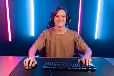 Kazanmak için çevrimiçi oyun oynayan akıllı flama makinesinin sunucu kanalı, neon ışıklı odada seçilen takım yarışması için izleyicilerle birlikte canlı yayında canlı yayında kulaklık takıyor. Bireysel.