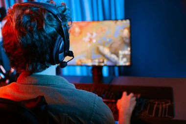 Savaş arenasında çoklu oyunlar takımıyla Moba 'da savaşan genç oyun flamasının sunucu kanalı, neon dijital ışık modern odasındaki arka görüntü ile bilgisayar monitöründe kulaklık takıyor. Toplayıcı.