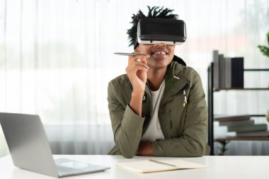 VR gözlükleriyle çalışan genç bir Afrikalı Amerikalı sanal dünyayı dijital gelecekteki sanal gerçekliğe bağlayan sanal dünyayı gösteren hologramla çevrimiçi kurslara katılıyor. Entrika.