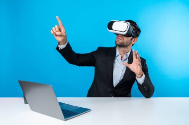Bilgisayarla masada otururken ve VR gözlüğü takarken veri analizine bakan yetenekli bir iş adamı. Proje yöneticisi sanal gerçeklik sistemini kullanarak ya da metaevrende bağlantı kurarak çalışıyor. Sapma.