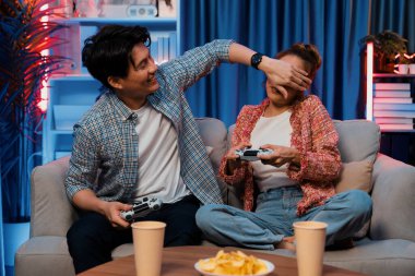 Oyun oynayan mutlu çiftin oturduğu kanepe joystickle oyun oynuyordu. Önden atıştırmalıklar ve kazanmak için gözlerini kapayan içkiler, evdeki modern neon ışıklı oturma odasında eğlenceli bir şekilde meydan okumaydı. İnfobahn.