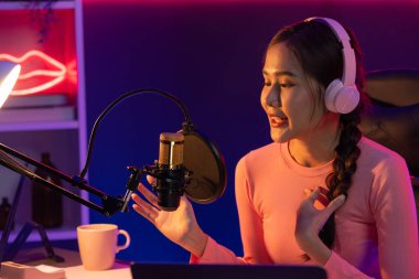 Geceleri podcast 'te olumlu konuşmalar yapan, pembe neon ışıklı modern stüdyoda sunum için dizüstü bilgisayar kullanan, gülümseyen, genç, güzel Asyalı bir etkileyiciydi. Taktik.