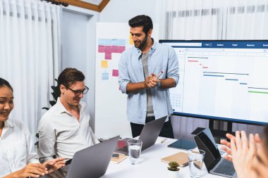 Proje yöneticisi monitörde proje yönetimi yazılım görüntülemesi, proje görevinin ilerlemesini izlemek ve toplantı masasında program planı yapmak suretiyle ekiple iletişim kurar ve işbirliği yapar. Tedbirli