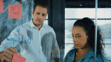 Yetenekli işadamı, cam duvara renkli yapışkan notlar yapıştırarak proje yöneticisine pazarlama fikrini sundu. Proje yöneticisi yatırımcıya projeyi gösteriyor, anlatıyor, gösteriyor. Yönlendirici.