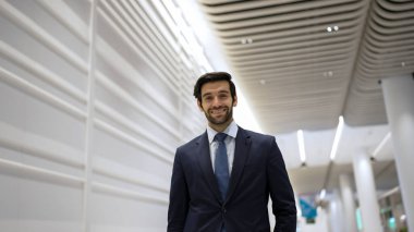 Gülümseyen iş adamı beyaz arka planda dururken kameraya bakıyor. İş elbisesi giyerken kameraya gülümseyen başarılı adamın yakın çekimi. Mutlu yönetici kameraya bak. Sevinçli..