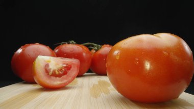 Macrography, slices of tomato rest elegantly on a rustic cutting board against a dramatic black background. Each close-up shot captures the juicy texture and rich colors of the tomatoes. Comestible. clipart