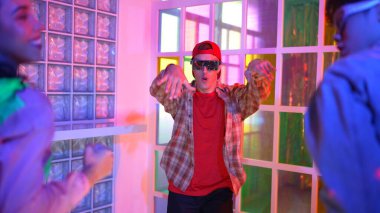 Kafkas dansçısı dans ederken çeşitli arkadaşları gece kulübünde neon ışıkta ayak seslerine bakıyor. Çoklu etnik kökenli hipsterin serbest stil müziğe geçişi ve mutlu bir adamın kameraya bakışıyla. Mutluluk.