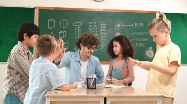 Zeki öğretmen, çeşitli çocuklar sınıf çalışması yapmak için birlikte çalışırken farklı çocukların zihin haritası çizdiği fikri açıklıyor. Çekici eğitmen öğretmek ve çalışmak hakkında konuşmak. Pedagoji.