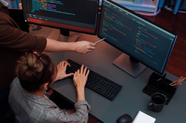 Akıllı web sitesi geliştirme kodlayıcı sistemi ile tartışan IT geliştiricilerinin üst görüşü modern ofisteki neon ışık odasında iki ekran bilgi teknolojisini çevrimiçi çalıştırıyor. İnfobahn.