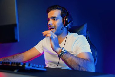 Akıllı oyun kurucusu, dijital neon ışıklandırma stüdyosundaki sosyal medya uygulamasında başkalarıyla iletişim kurmak için kulaklık ve mikrofon kullanan takım üyeleriyle konuşuyor. Tahmin et..