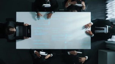 VR kulaklık takan çeşitli veri analistlerinin üst görüşü, program hologramını kodlarken, aynı zamanda yönetici dizüstü bilgisayarından gelen programlama mühendisliği komutlarını manipüle etmek için el hareketleri kullanıyor. Müdürlük.