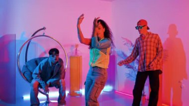 İspanyol hipster renkli kıyafetler giyer ve serbest stil müziğe el sallar. Profesyonel break dansçı neon ışıklarıyla ve modern stüdyo arkadaşlarıyla coşkuyla dans ediyor. Mutluluk.
