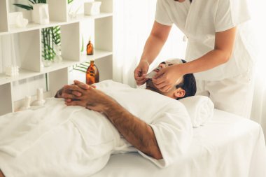 Kaplıca salonunun sakin, modern gündüz atmosferi. Kadın müşteri yüz maskesi takarak kendini yenilemeye çalışıyor. Yüz bakımı ve güzellik kozmetolojisi prosedürü. Sessiz.