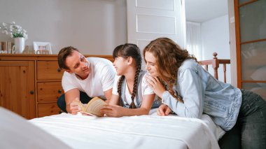 Çocukluk hikayeleri anlatan uyku zamanı, anne ve baba rahat ve rahat yatak odasındaki küçük kızlarına birlikte fantezi kitabı okuyorlar. Modern aile eğlencesi. Eşzamanlama