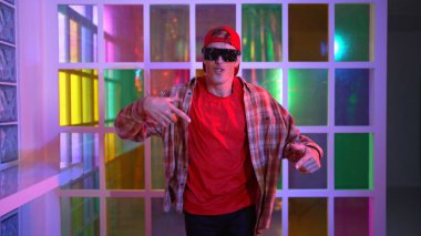 Komik break dansçı kameraya bakarken hiphop 'a doğru serbest adım atıyor. Çılgın mutlu hipster dans edip sokak dansı yaparken Led ışığında günlük kıyafet ve güneş gözlüğü takıyor. Mutluluk.