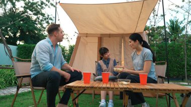 Family all together sit at camp in garden then having a meal. Lovely parent use outdoor camping activity as way to communicate and spending time with young generation cross generation gap. Divergence. clipart