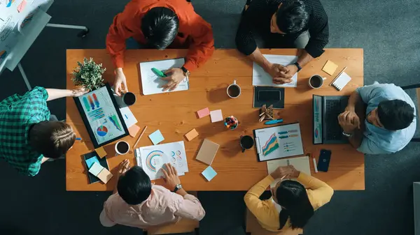 İş kadını tabletinin en üst görüntüsü finansal grafik ve toplantı masasında yapışkan notlarla duruyor. Proje yöneticisi borsa istatistiklerine ve veri analizlerine bakıyor. Cemaat.