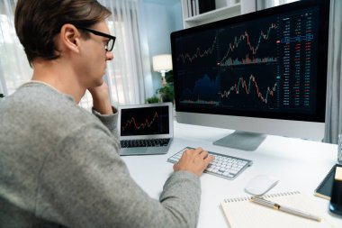 Bilgisayar ve dizüstü bilgisayarı kullanarak, çalışma masasındaki dinamik artırılmış borsa grafiğinin en yüksek kar değerini araştıran bir tüccar, modern ofisteki ekrandaki döviz kuru değerini analiz ediyor. Bireysel.