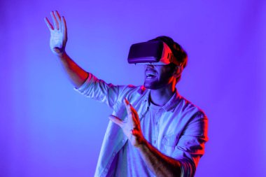 Heyecan verici bir sporcu el hareketi yaparken VR gözlüğü takıyor. Yetenekli genç ayakta duruyor ve teknolojik yenilikleri kullanarak gelecekteki sanal dünya programını veya metaevreni inceliyor. Sapma.