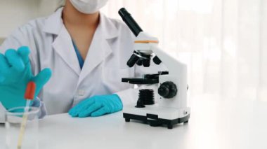 Bilimsel laboratuar araştırmacısı mikroskobik slayt üzerine sıvı örneği bırakır. Tıbbi muayene için ya da yeni teşhis aleti için. Mikrobiyolog ya da tıp çalışanı laboratuarda deney yapıyor. Ağır çekim. Katı.