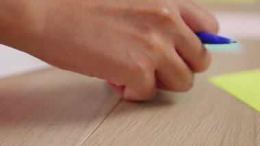 Yavaş çekimde, kadın iş kadını el yazısı pazarlama kâğıdı üzerine kalem ve yapışkan notlarla masaya yerleştirilmiş. Yaratıcı bir girişim ve takım çalışması konsepti. Eline odaklan. Değiştirilmiş.