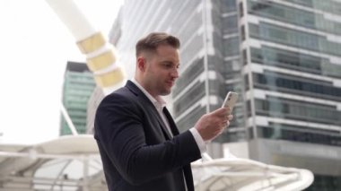 Kafkasyalı iş adamı şehir merkezinde dururken cep telefonlarını kontrol ediyor ve pazarlama ekibinden satış raporlarını inceliyor. Yetenekli bir yönetici cep telefonu üzerinde çalışıyor ve veri analizine bakıyor. Urbane.