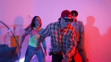 Çeşitli arkadaşlarla sokak dansı pratiği yapan profesyonel break dansçı. Çok kültürlü mutlu insanlar modern dans ederken şık giysiler giyer veya hippi tarzı dans ederler. Neon ışığı. Mutluluk.