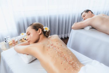 Lüks spa salonlarında sıcak mum ışığında cilt bakımı gören mutlu çift müşterisi. Sağlık kaplıcasında güzellik tedavisiyle tuz temizliği. Sessiz.