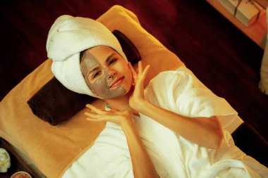 Kaplıca salonunun sakin atmosferi, üst düzey kadın müşteri sıcak mum ışığında kömür kömürü yüz kremi masajıyla kendini yenilemeye çalışıyor. Yüz bakımı ve güzellik konsepti. Sessiz.