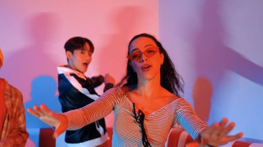 Çok kültürlü bir arkadaş birlikte dans ediyor ve hiphop müziği eşliğinde restoranda ya da kafede pembe neon ışıklı duruyor. Profesyonel sokak dansçıları grubu enerjik hareketler sergiliyor. Mutluluk.