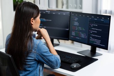 Genç Asyalı bilişim geliştiricisi güzel poz için online bilgi topluyor. Kodlama programı verileriyle birlikte kotlu tişört giyiyor. Güvenlik analizi ile çevrili iki ekran. Taktik.