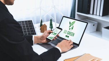 Ofiste çalışan iş adamı, CSR 'ın dışında daha yeşil bir çevre için bilgisayar ekranında güneş pili teknolojisiyle çevre dostu alternatif enerji planı veya projesi geliştiriyor. Döngü