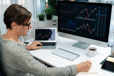 Bilgisayar ve dizüstü bilgisayarı kullanarak, çalışma masasındaki dinamik artırılmış borsa grafiğinin en yüksek kar değerini araştıran bir tüccar, modern ofisteki ekrandaki döviz kuru değerini analiz ediyor. Bireysel.