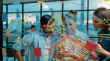 Bir grup profesyonel iş adamı birlikte çalışarak pazarlama fikri, planı, stratejisi ve renkli yapışkan notlarla cam duvarda çalışma ve yazma konularını tartışıyor. İzleme