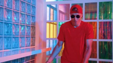 Komik break dansçı kameraya bakarken hiphop 'a doğru serbest adım atıyor. Çılgın mutlu hipster dans edip sokak dansı yaparken Led ışığında günlük kıyafet ve güneş gözlüğü takıyor. Mutluluk.