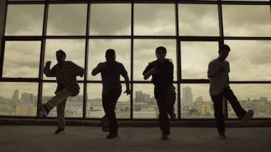 Yetenekli koreograf grubunun gökyüzü dövüşçüsüyle dans ederken çekilmiş siluet fotoğrafı, şehir manzarası arka planı. Genç hipster takımı dans gösterisi. Sepia filtresi. Gölge. Açık hava sporu 2024 hiphop..