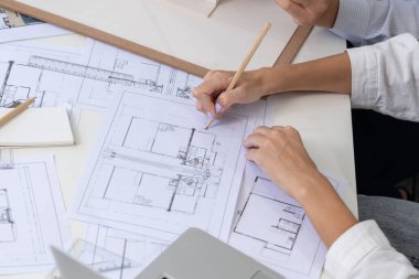 Asyalı kooperatif iş arkadaşı ev modelini ev modeliyle ve bina planıyla birlikte masaya koyarken, profesyonel güzel mimarın el yapımı taslaklarının en üst görüntüsü. Tertemiz..