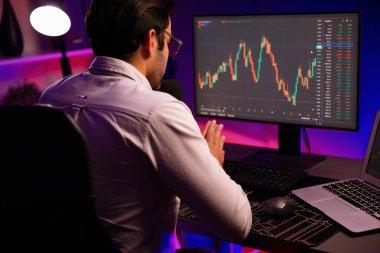 Akıllı tüccar işadamı, karanlık oda gecesinde neon ışıklı ofisteki arama pazarında yüksek kârla ekranda bilgisayar ve bilgisayar üzerinde dinamik borsa yatırımları üzerinde yoğunlaşıyor. Tahmin et..