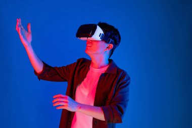 VR gözlüklerinden bakan zeki Asyalı adam, yenilikçi teknolojide dokunmatik ekran ile 3D hologram meta arayüzünü analiz ederek metazıt doğrultuda araştırma dizini verilerine dönüyor. Entrika.