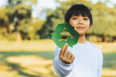 Cheerful young asian boy holding recycle symbol on daylight natural green park promoting waste recycle, reduce, and reuse encouragement for eco sustainable awareness for future generation. Gyre clipart