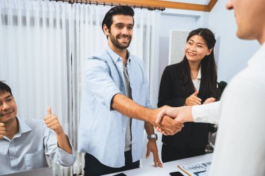 Çeşitli ofis çalışanları stratejik iş pazarlama toplantısı üzerine anlaşma yaptıktan sonra el sıkışıyor. Takım çalışması ve olumlu tutum verimli ve destekleyici bir iş yeri yaratır. Tedbirli