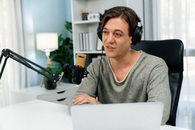 Sunucu kanalı, gülümseyen akıllı yayıncı kaydı, senaryosu ve akıllı telefonuyla sosyal medyada sohbet programı, kulaklık takarak modern ev stüdyosundaki video flamalarını kaydediyor. Bireysel.